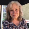 Juli Cobb in 2024. She's seated outdoors and is photographed from about the shoulders up. She has shoulder-length hair and is wearing a multicolored top.