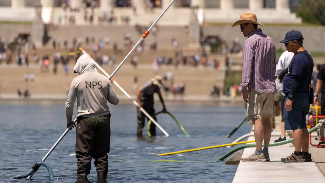 Visitors watch as National Park Service employees use vacuums to clean the Lincoln Memorial Reflecting Pool, Saturday, June 20, 2026, in Washington.