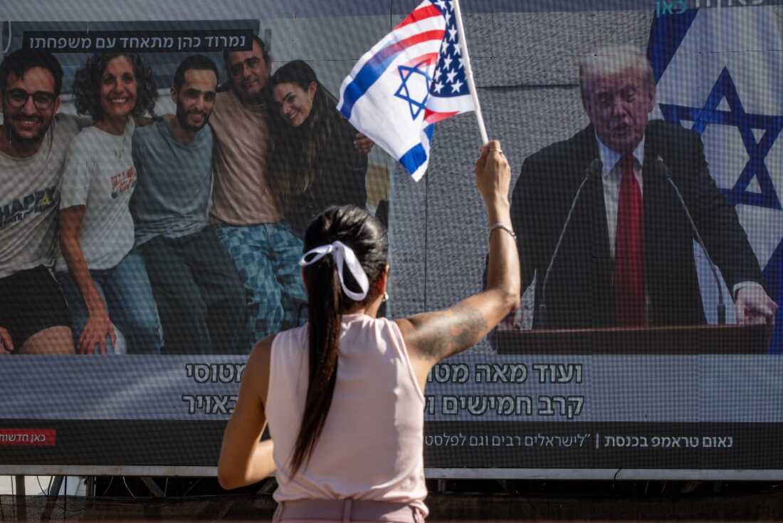 A woman waves a flag made of the U.S. and Israeli flags as she watches President Trump address the Knesset, Israel's parliament, on a giant screen in Hostage Square in Tel Aviv, Israel, on Monday. October 13, 2025 in Tel Aviv, Israel. The ceasefire deal between Israel and Hamas has brought an end to the two years of war that followed the attacks of Oct. 7, 2023. A condition of the deal was the immediate return of 48 hostages held in Gaza, around 20 of whom were believed to be alive. (Photo by Chris McGrath/Getty Images)