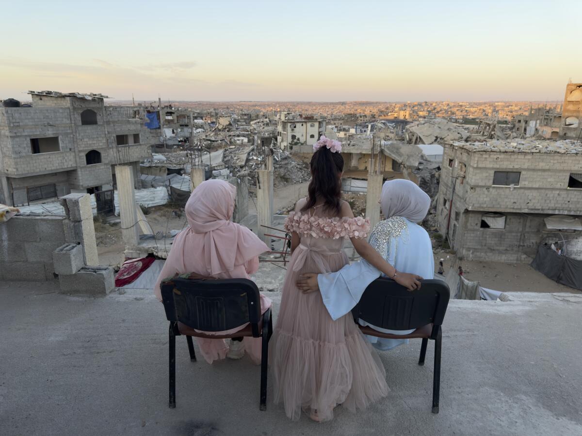 Three sisters sit looking out over a sea of debris as the sun sets in northern Gaza's militarized orange zone of Beit Lahia, on May 31.