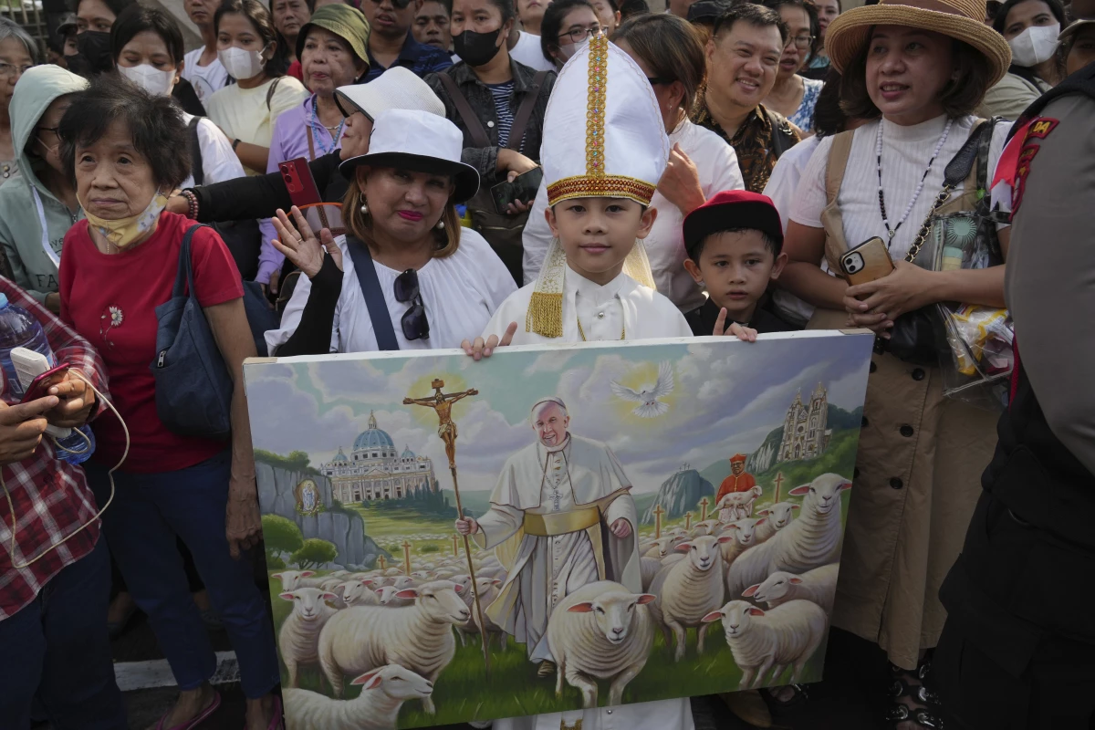 Worshipers hold a painting as they wait for Pope Francis outside the Cathedral of Our Lady of the Assumption, in Jakarta, Indonesia, Wednesday.