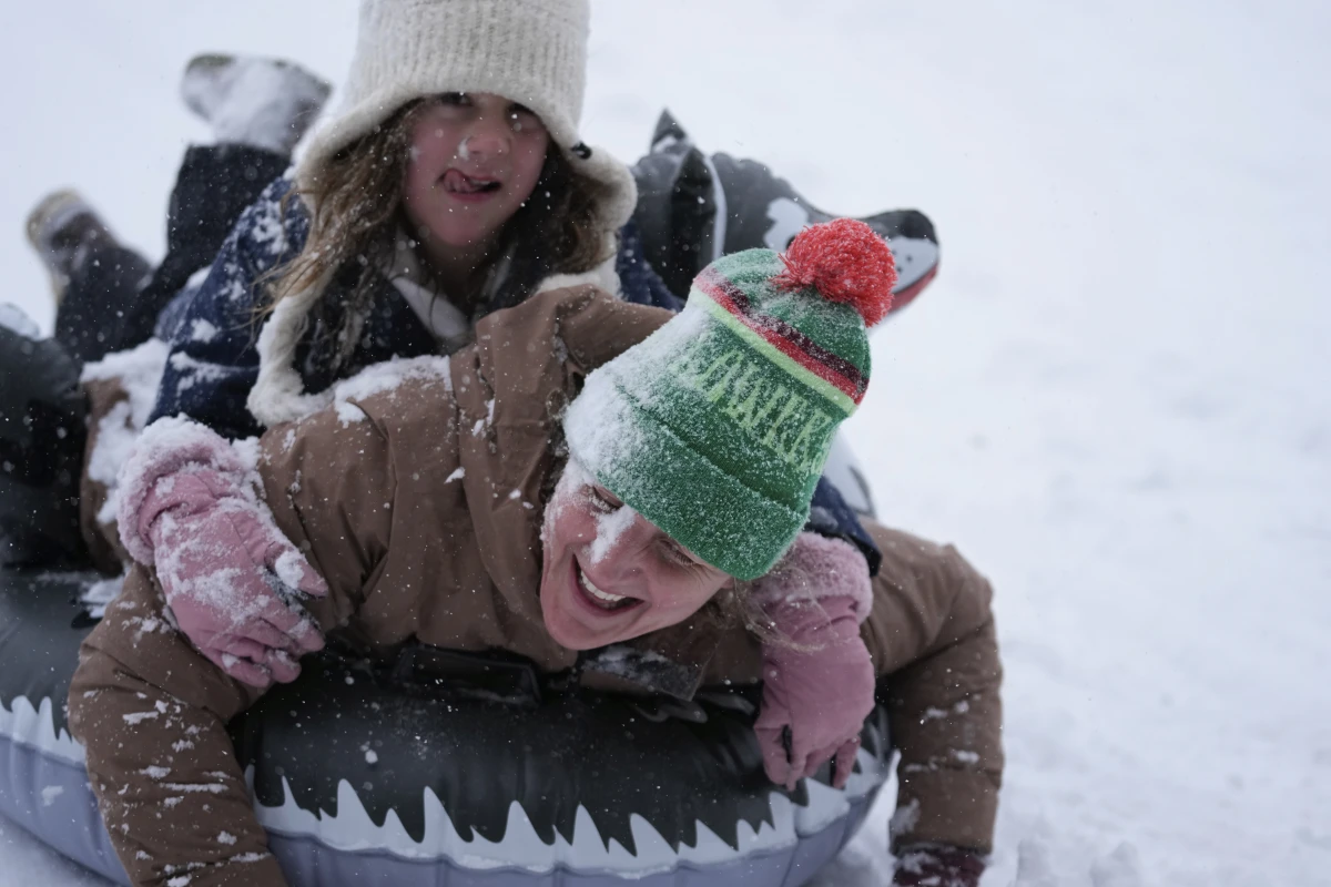 Houston, Texas: Abbie Schuh and her 8-year-old daughter Louise Delisio get covered in snow as they sled down a hill at Herman Park on Jan. 21.