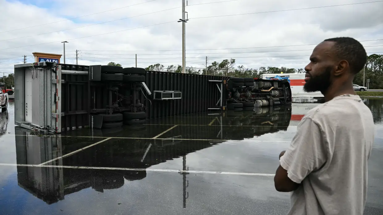 A driver look at his overturned truck in a flooded parking lot on Saturday morning in Tiger Point, Fla., close to where Hurricane Isaias made landfall Friday night.