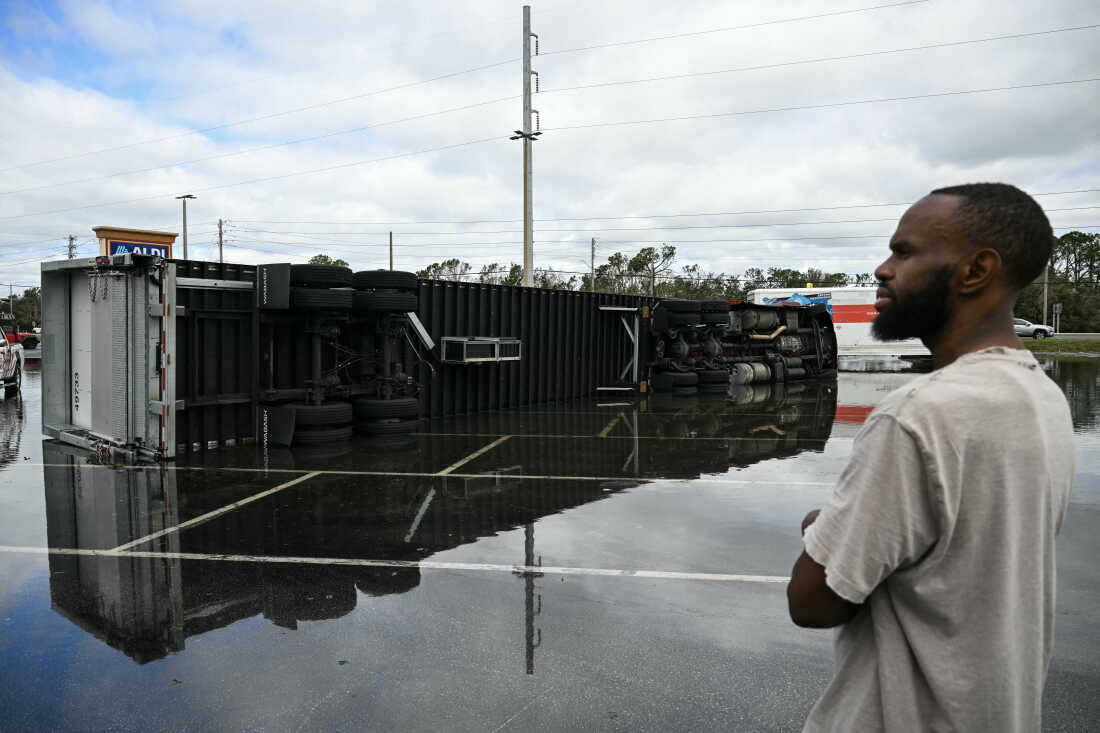 A driver look at his overturned truck in a flooded parking lot on Saturday morning in Tiger Point, Fla., close to where Hurricane Isaias made landfall Friday night.