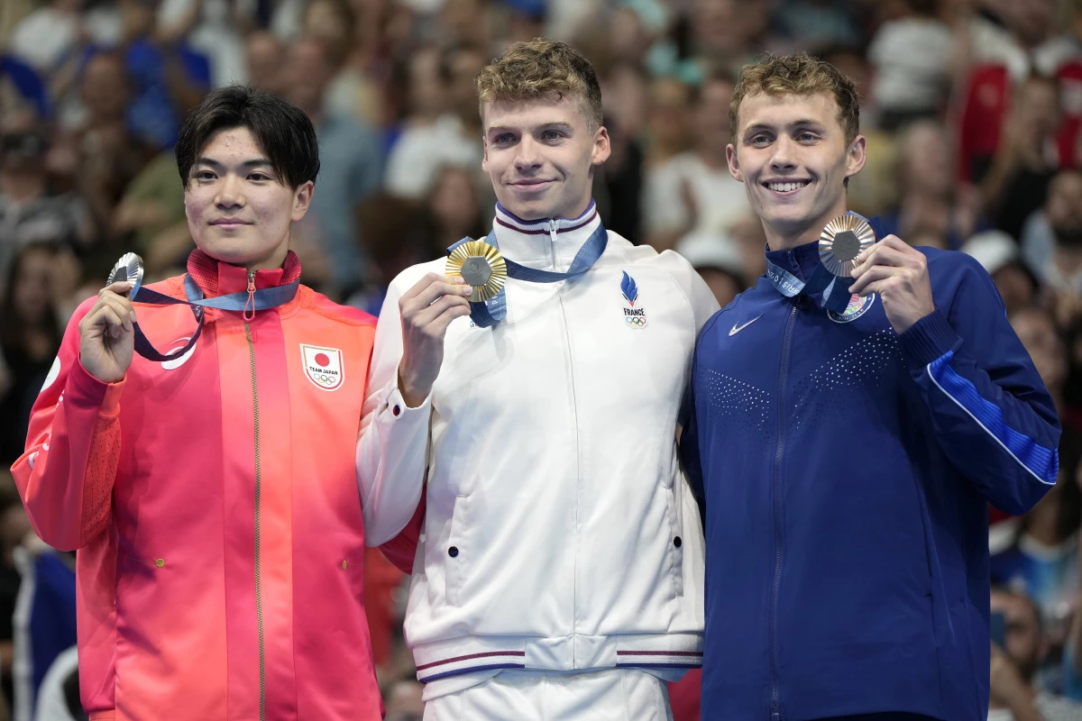Gold medalist Leon Marchand, center, of France, stands with silver medalist Tomoyuki Matsushita, left, of Japan, and bronze medalist Carson Foster, of the United States, following Sunday's men's 400-meter individual medley final.