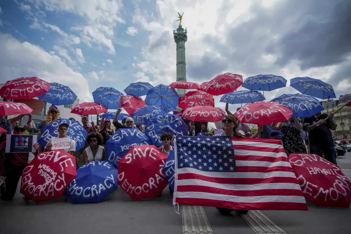 Paris, France: People holding umbrellas reading save democracy take part in the No Kings protest.