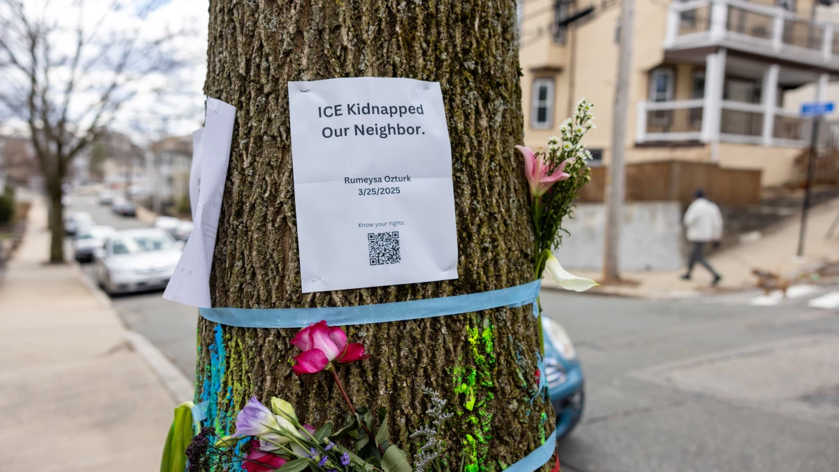 Signage and flowers are placed on a tree next to where ICE agents apprehended Tufts University graduate student Rumeysa Öztürk on March 25 in Somerville, Mass.