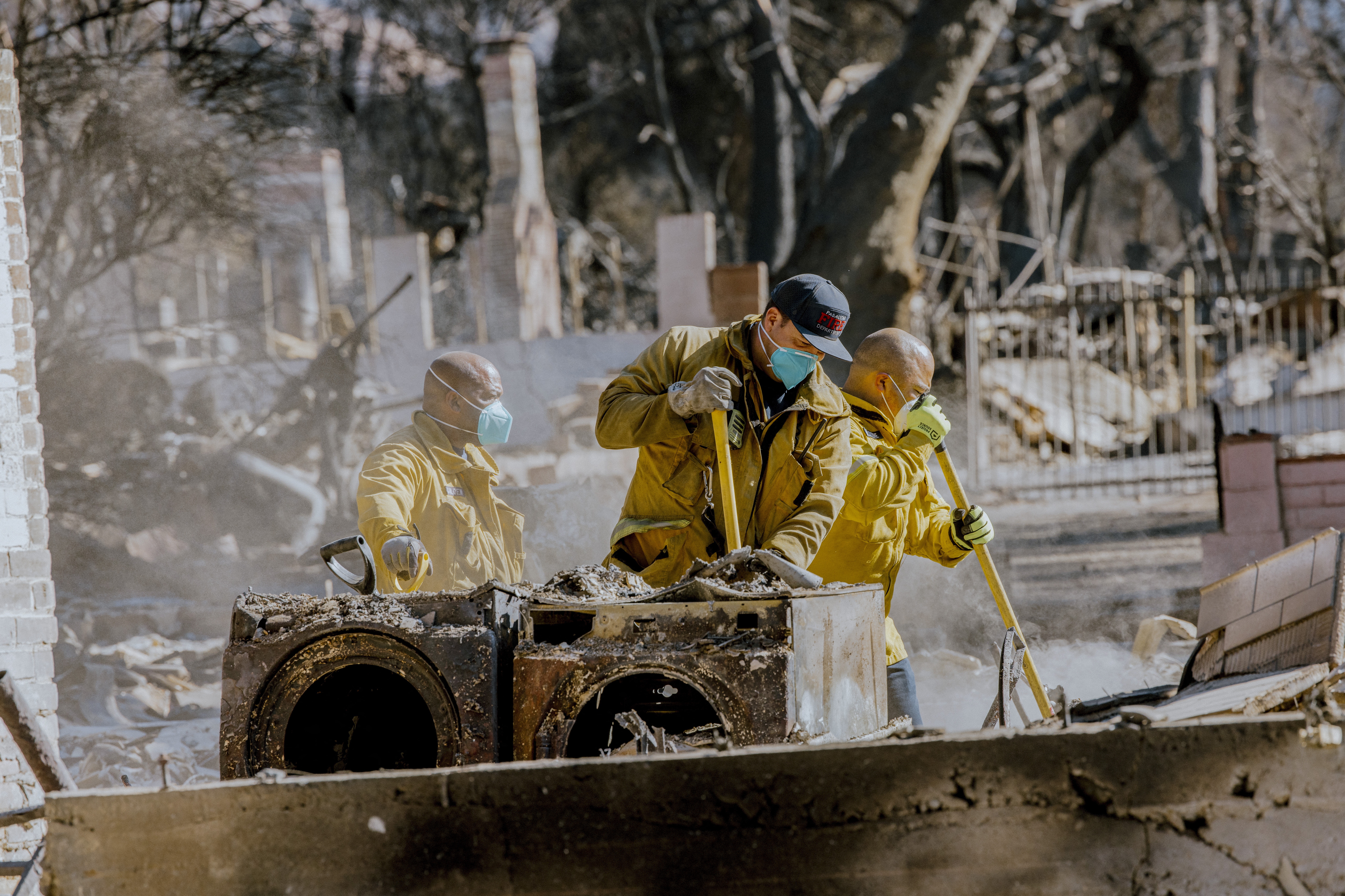 Firefighters clean up after the Eaton Fire in California. Health experts recommend wearing particle-filtering masks, goggles, gloves, and other personal protective equipment while cleaning up the potentially toxic ash and smoke after the burn.