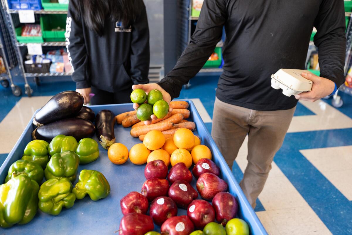 Visitors to the Island Oasis sort through the pantry's fresh produce offerings. One parent, John, said the pantry and the grocery store cards he's received from Mainzer have 'made a huge difference' for him and his son.