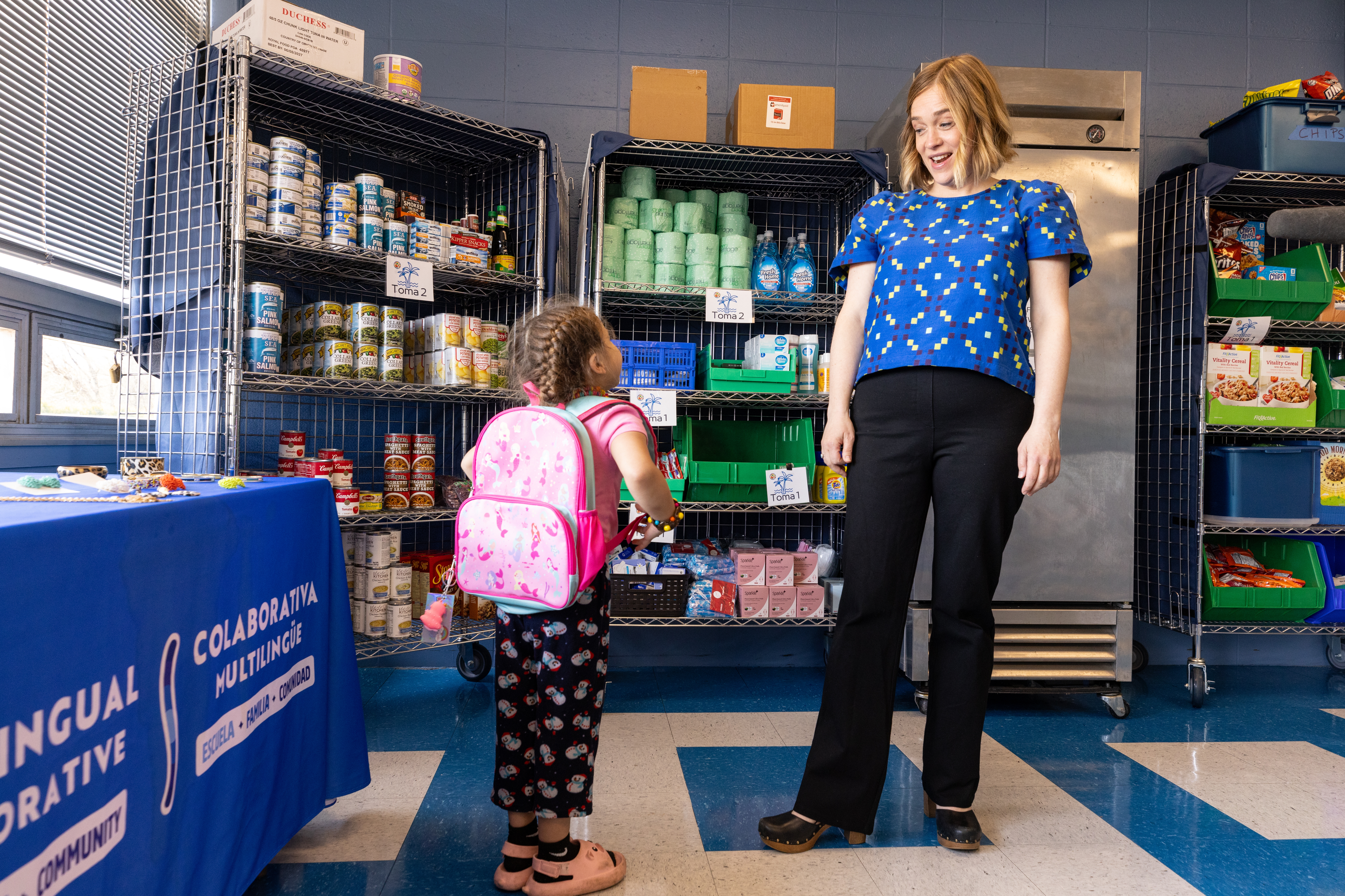 Megan Mainzer, the McKinney-Vento liaison for Middletown Public Schools in Rhode Island, speaks with a young girl at the Island Oasis, a food and clothing pantry that