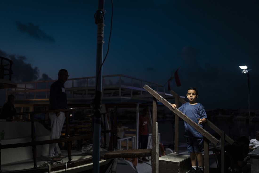 Tyre, Southern Lebanon — June 7, 2026. Displaced people spend the evening in the Christian port area of Tyre. Israeli airstrikes have targeted residential neighborhoods, leaving some areas empty as residents flee within minutes, while others remain, bound to their homes and livelihoods. The escalation between Israel and Hezbollah has displaced more than one million people, deepening an already severe humanitarian crisis and complicating ceasefire efforts. Diego Ibarra Sánchez for NPR