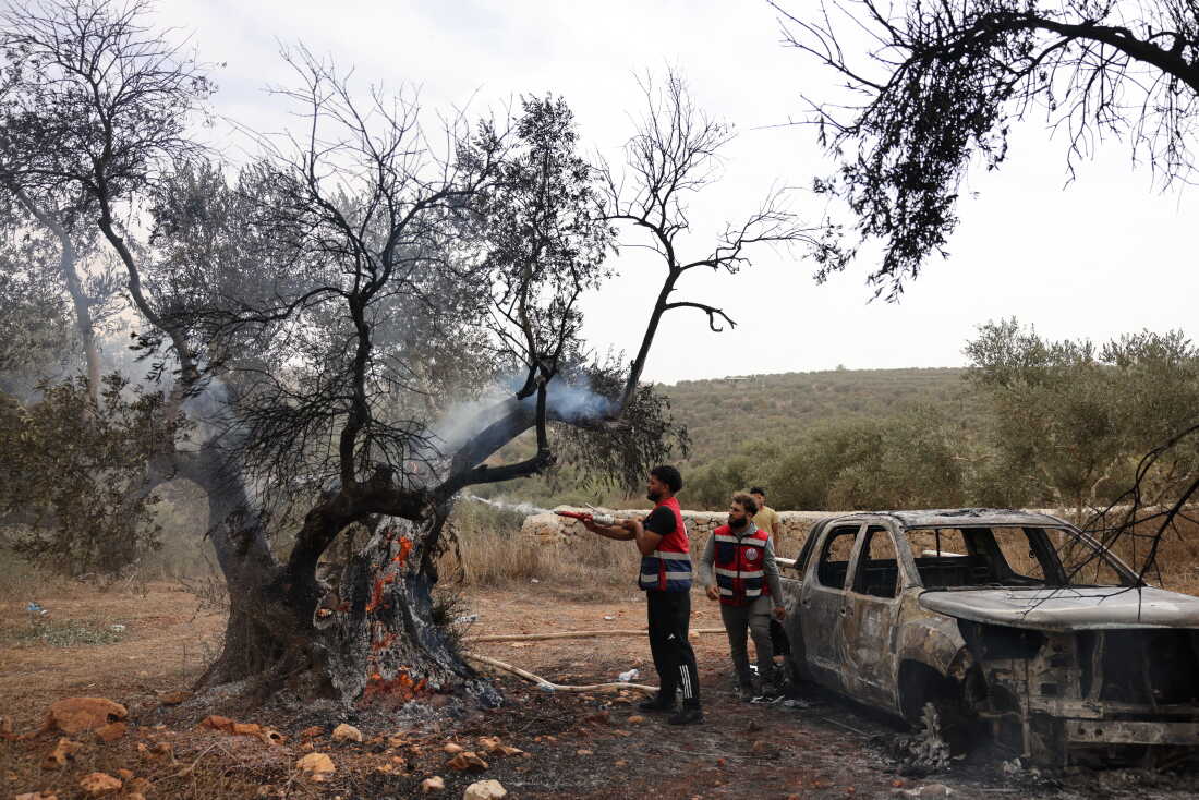 Palestinian volunteers douse an olive tree set on fire along with a Palestinian-owned vehicle, reportedly by Israeli settlers, near the village of Turmus Ayya, north of the city of Ramallah, in the Israeli-occupied West Bank, on Friday.