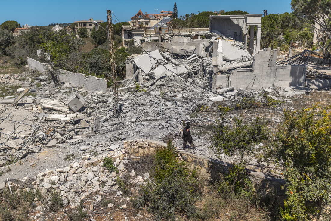 On July 28, 2026, a Lebanese woman walks through a devastated landscape in Zawtar al-Gharbieh, southern Lebanon, following the withdrawal of Israeli forces. Lebanese residents were forced to leave their homes for months but are now slowly returning to their devastated town.