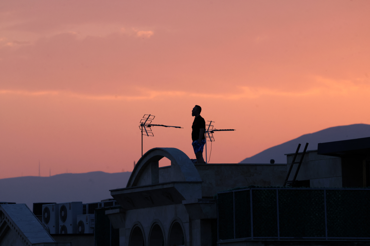 A man stands on the roof of a building while watching the horizon in Tehran on June 16. Iran's state broadcaster was briefly knocked off the air by an Israeli strike and explosions rang out across Tehran that day.