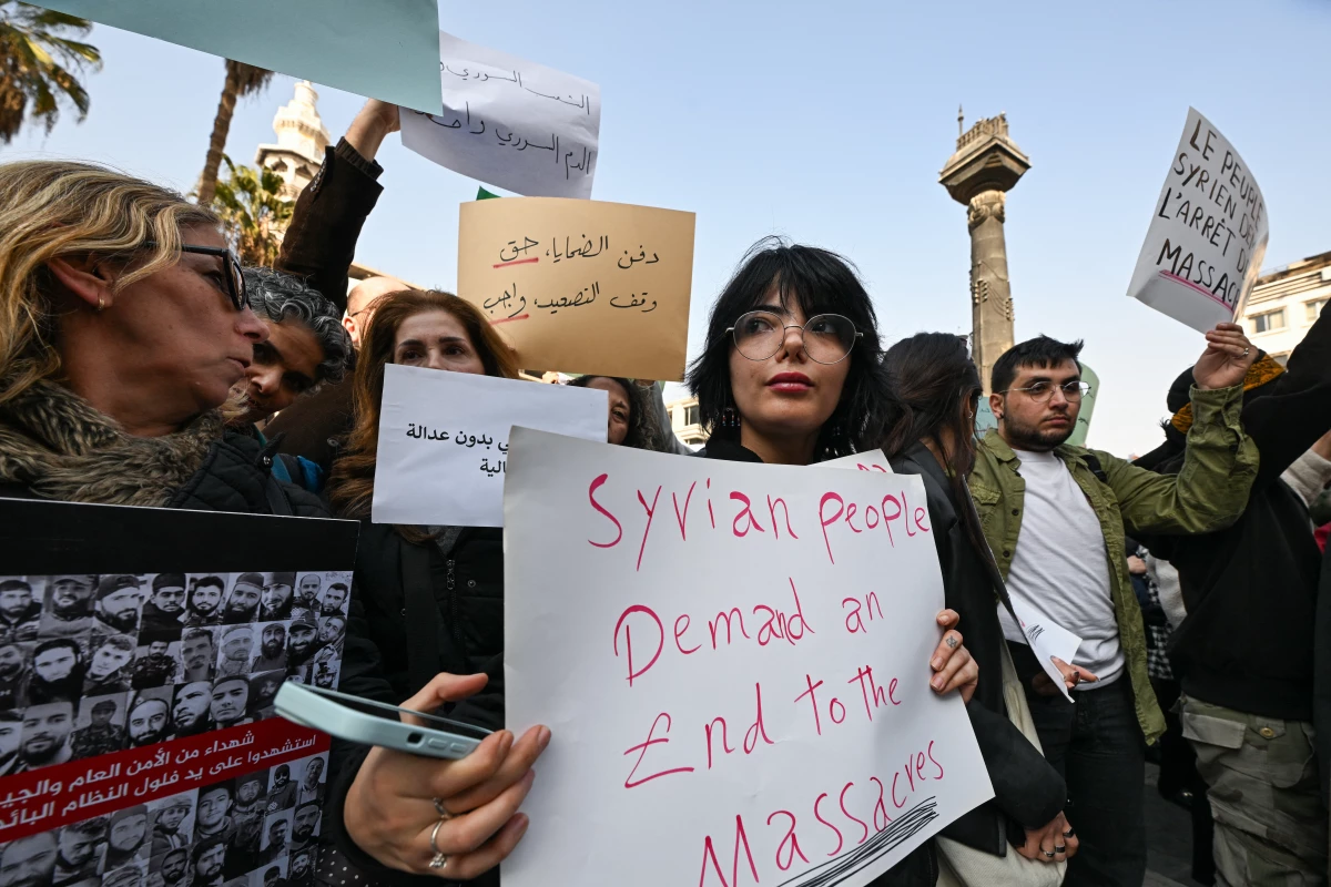 People lift placards during a rally called for by Syrian activists 'to mourn for the civilian and security personnel casualties,' at al-Marjeh square in Damascus on March 9.