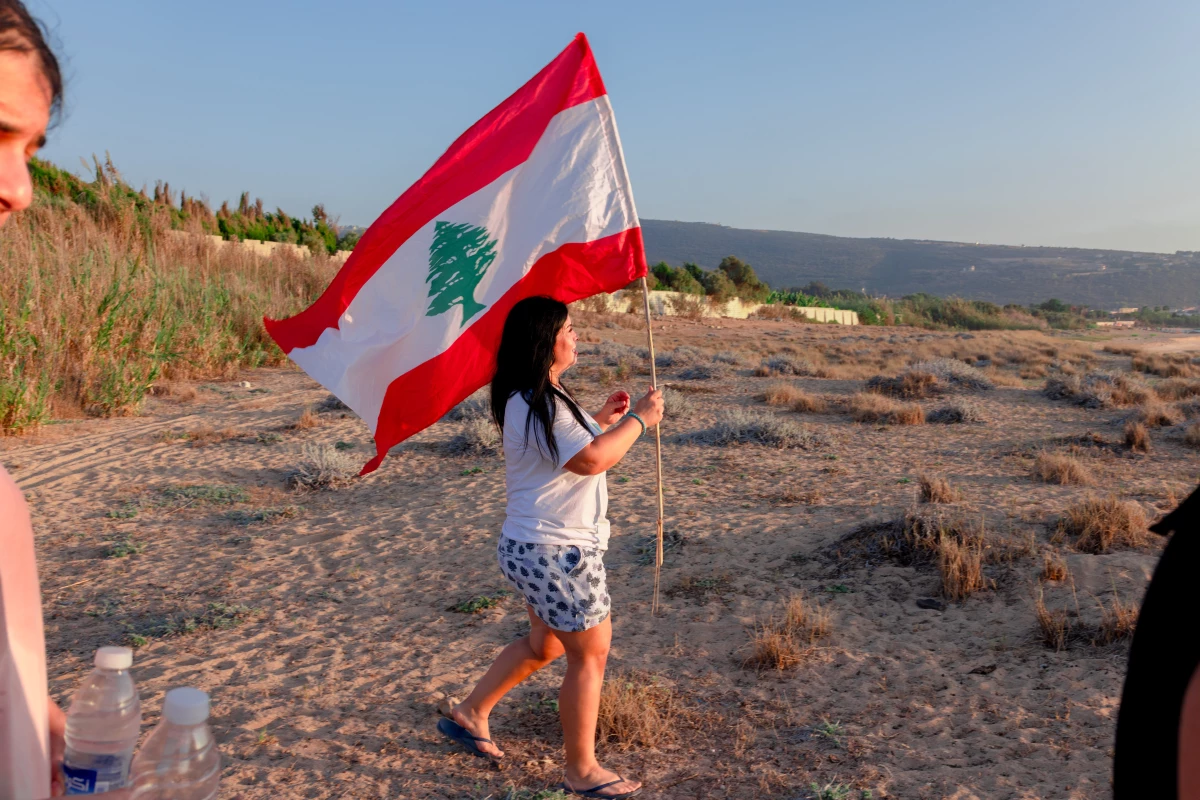 Fadia Joumaa carries Lebanon's national flag as she leads a group of volunteers trying to protect sea turtles on Mansouri Beach.