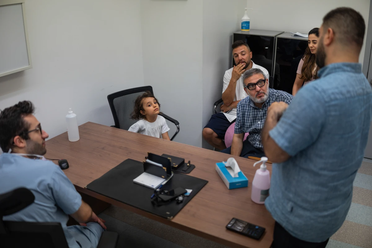 Kenzi Madhoun and her father (in the white shirt) meet with Dr. Ghassan Abu-Sittah (seated, in the plaid shirt) as he and his medical team decide on the surgical plan that will allow her to be fitted with the best artificial limb possible.