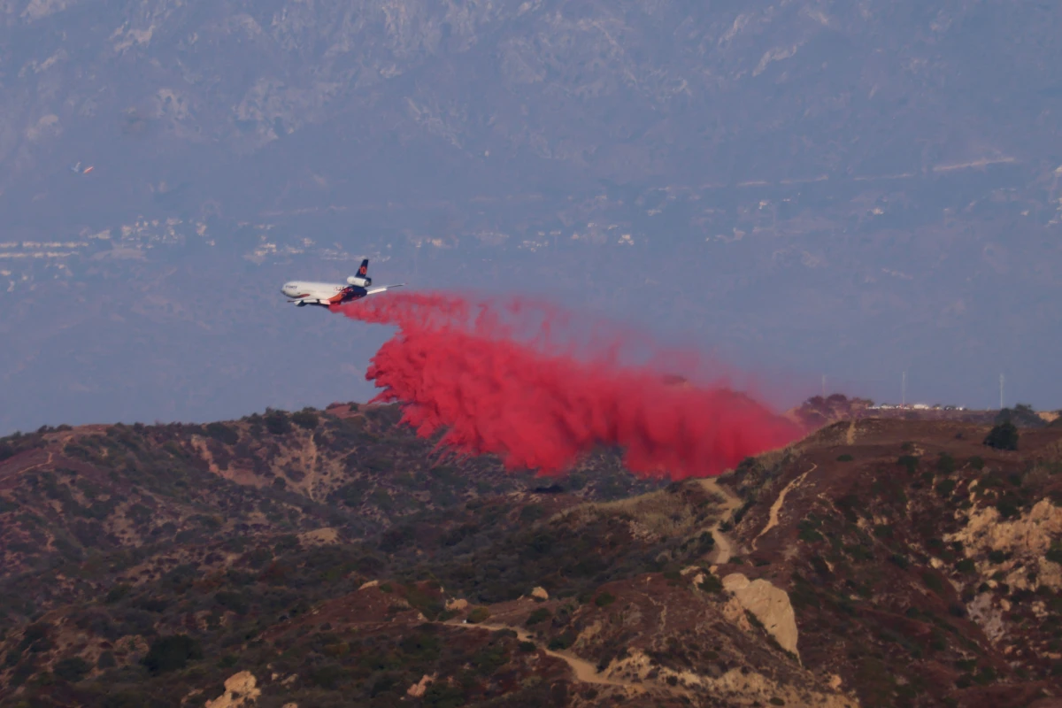 A tanker drops retardant as the Palisades Fire grows in the mountains in Topanga, Calif., on Thursday