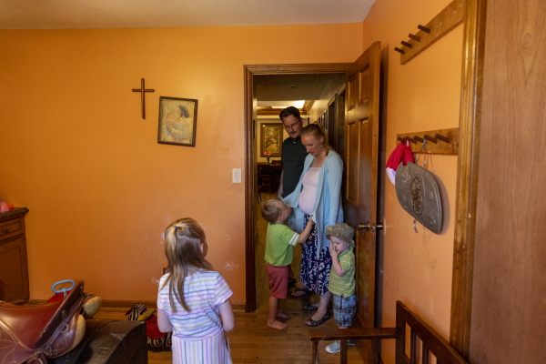 In this photo, three of the younger Alger children stand in a playroom at their home. Their pregnant mother stands in the doorway, and their father stands behind her.