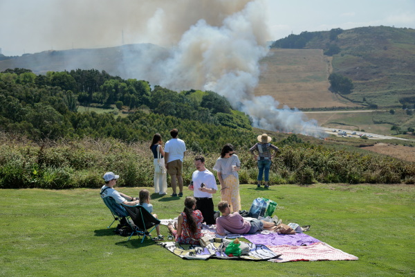 People watch as a wild fire climbs a hill near where thousands are set to gather for the total solar eclipse at El Monte De San Pedro park in A Coruna, Spain.