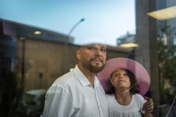 Beirut, Lebanon. August 11, 2025. Six-year-old Kenzi Madhoun from Gaza poses with her father, Adam, outside the American University of Beirut Medical Center. She arrived in Beirut to begin treatment after being injured in Gaza on Oct. 21, 2023, and is among nearly 35 children brought to Lebanon by the Ghassan Abu Sittah Children’s Fund for medical and psychological support. Diego Ibarra Sánchez for NPR