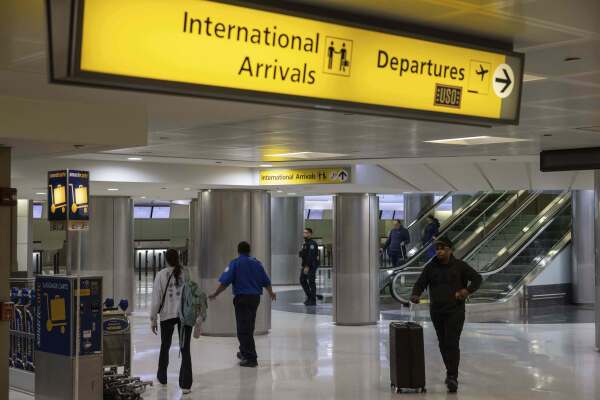 Travelers ⁣pass through Newark Airport's international terminal ⁢after president ⁢Trump's new travel ban took effect.