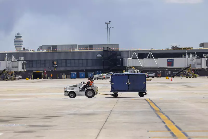 A Delta Air Lines employee drives an aircraft tug with a luggage cart on the tarmac at Atlanta Hartsfield Jackson International Airport.