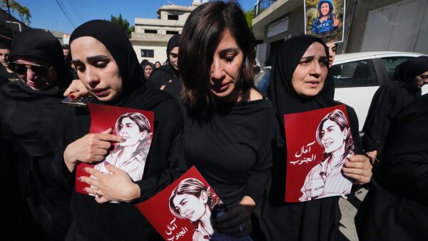 Mourners hold posters that show portraits of Lebanese journalist Amal Khalil, who was killed Wednesday in an Israeli airstrike, during her funeral procession in the village of Baysariyeh, in southern Lebanon.