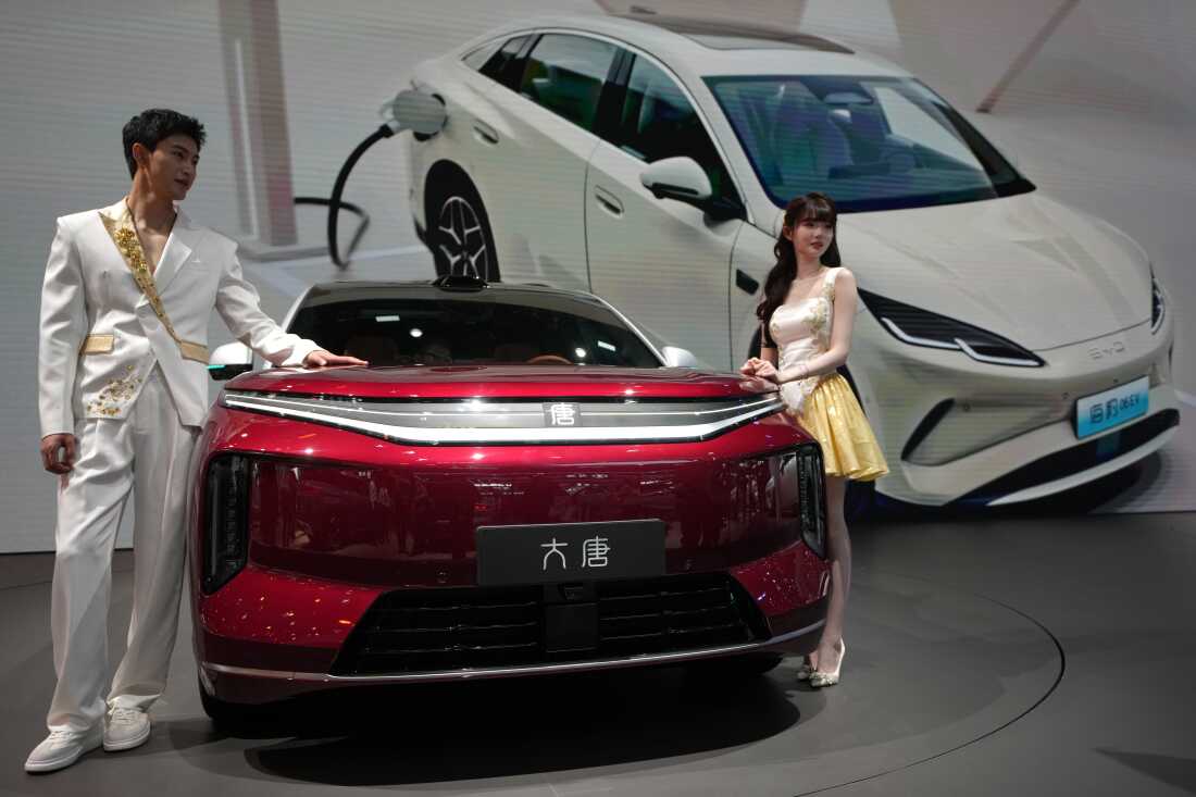 FILE - Models stand next to a latest EV car from Chinese automaker BYD showcased at the Auto China 2026, in Beijing, April 25, 2026.