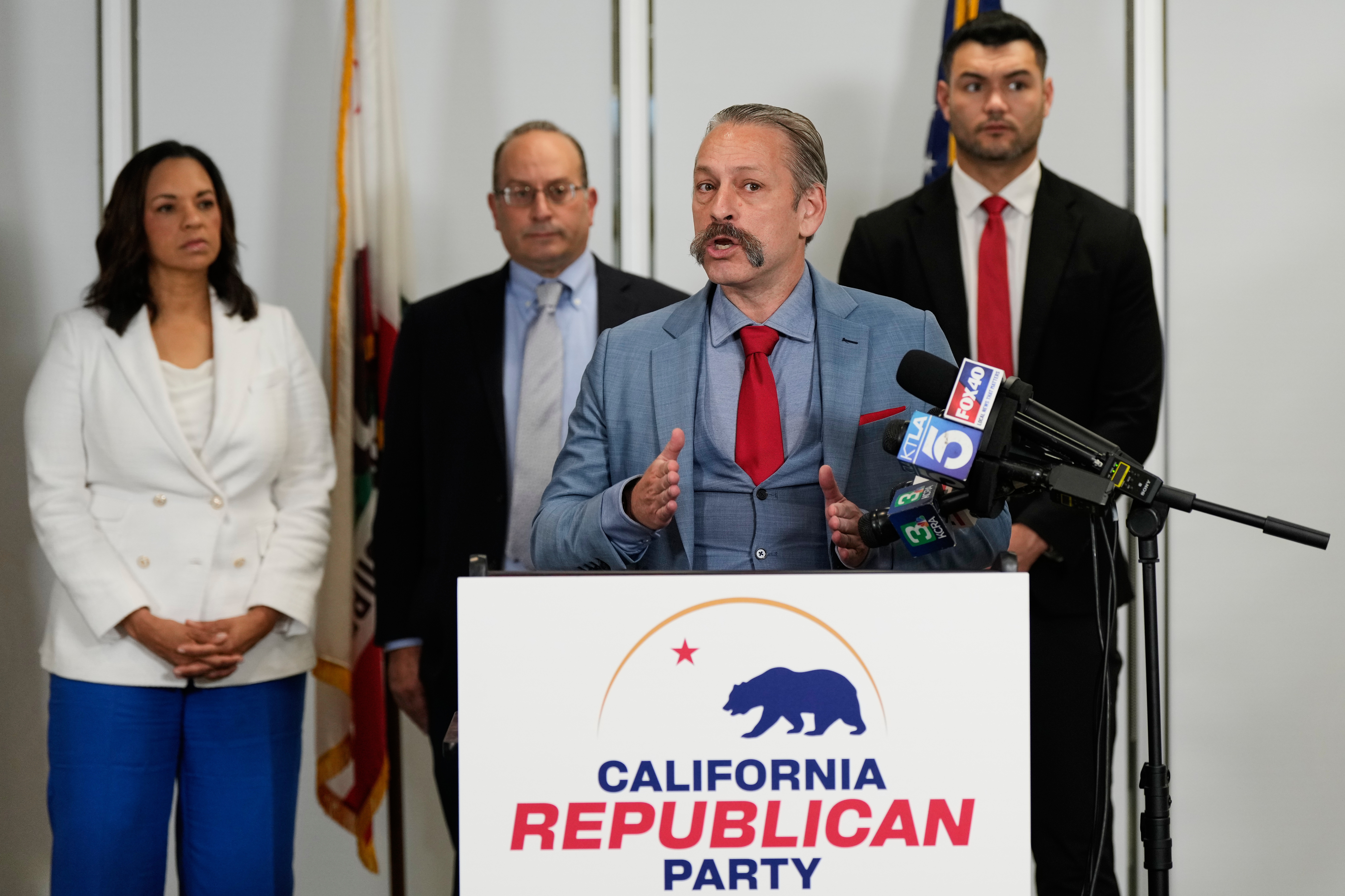 Attorney Mark Meuser, second from right, speaks to reporters during a press conference announcing a federal lawsuit in November challenging Proposition 50, in Sacramento, Calif.