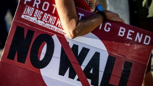 A woman hold's a sign to protest the plans by President Trump's administration to build a section of the border wall at the Big Bend National Park in Study Butte, Texas, on August 15, 2026.