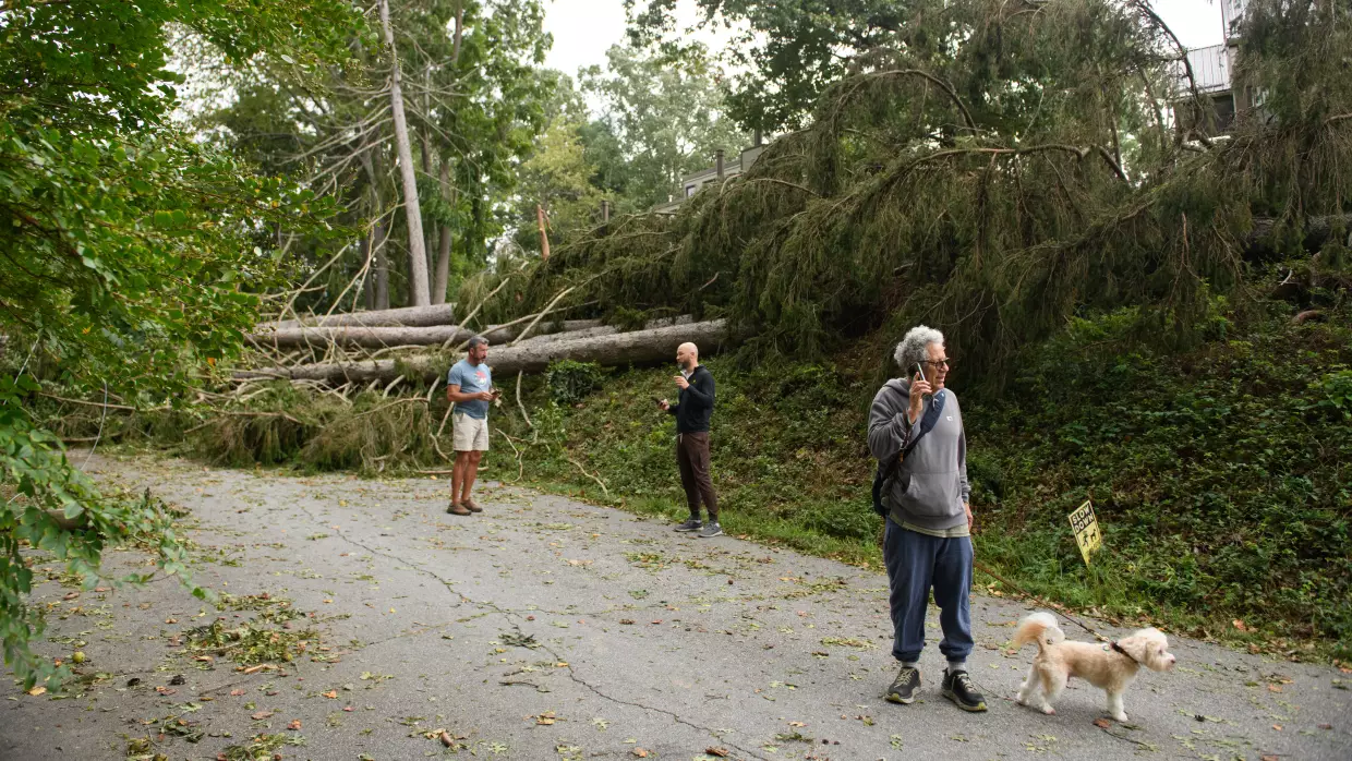 Residents make phone calls in their neighborhood after heavy rains from hurricane Helene caused record flooding and damage on September 28, 2024 in Asheville, North Carolina.