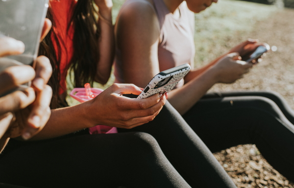 Three women sit down looking at their smartphones.
