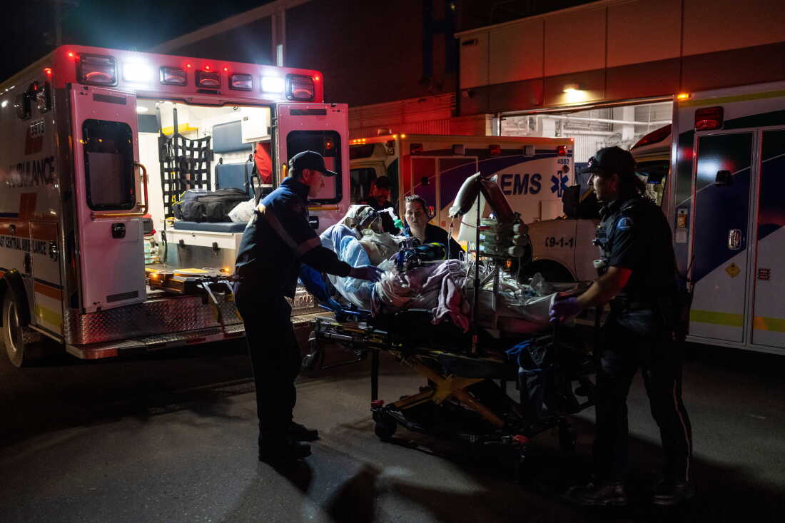 Paramedics load an injured person into an ambulance at the Wainwright Health center after a fire at Canadian Forces Base Wainwright, outside of Wainwright, Albe