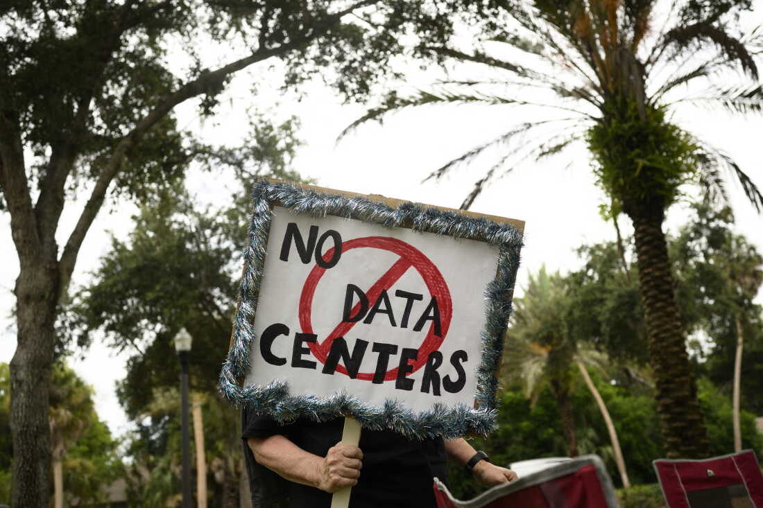 A person holds signs during a nationwide protest against AI data center expansion in New Port Richey, Florida on July 18, 2026.