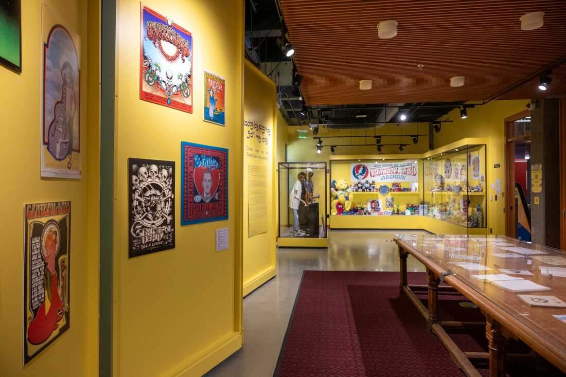 This exhibition space with yellow walls displays Grateful Dead memorabilia such as posters, paper documents and a yellow teddy bear.