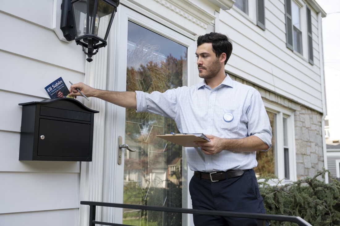 Democrat Eli Sabin, 26, who's running for state representative in Connecticut, places a campaign flyer into a voter's mailbox.