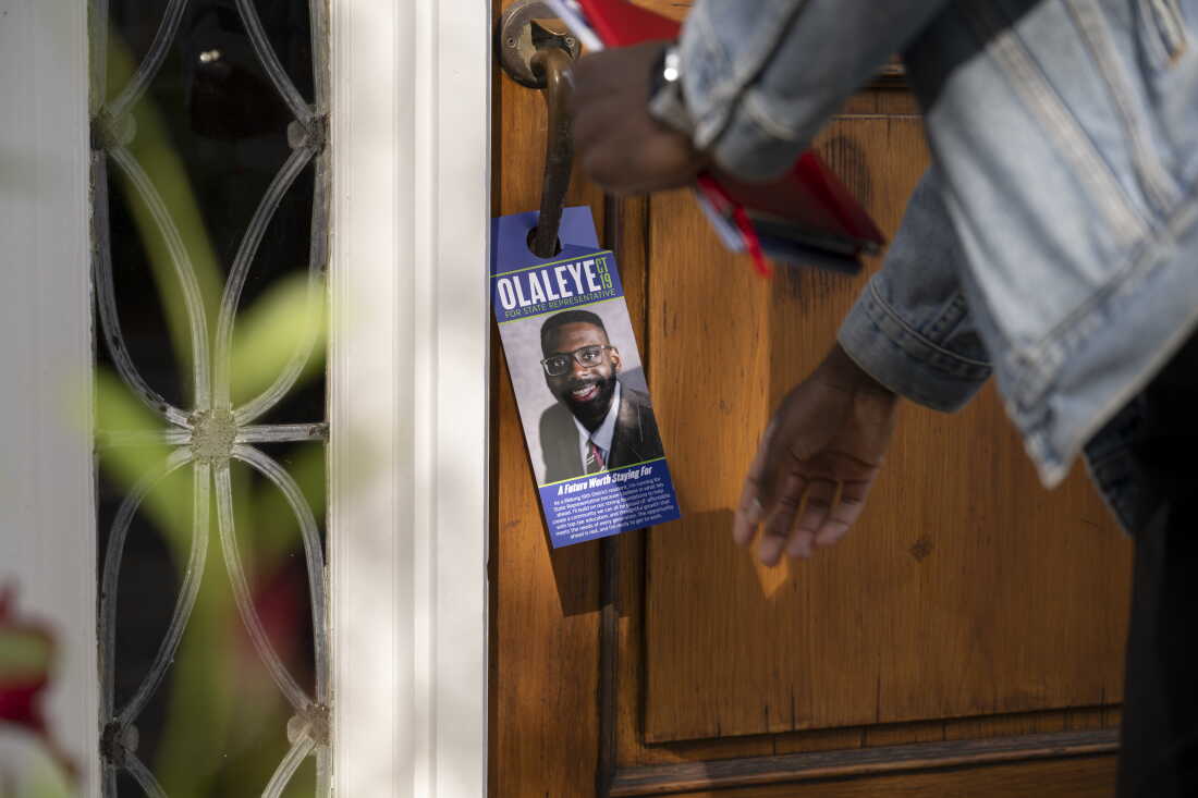 Olaleye Onikuyide leaves a campaign flyer on the door handle of a voter’s home in West Hartford.