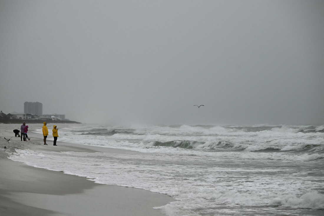 People watch as waves build near the Pensacola Beach Gulf Pier in Pensacola Beach, Florida, on October 9, 2026, as Hurricane Isaias continues moving north toward the Florida Panhandle. Hurricane Isaias intensified to Category 2 in the Gulf of Mexico's warm waters on Thursday as it churned toward the southern United States, the National Hurricane Center (NHC) said. The first hurricane of the Atlantic season, Isaias is forecast to make landfall in Florida, Alabama or Mississippi overnight Friday to Saturday, according to the NHC. (Photo by RONALDO SCHEMIDT / AFP via Getty Images)
