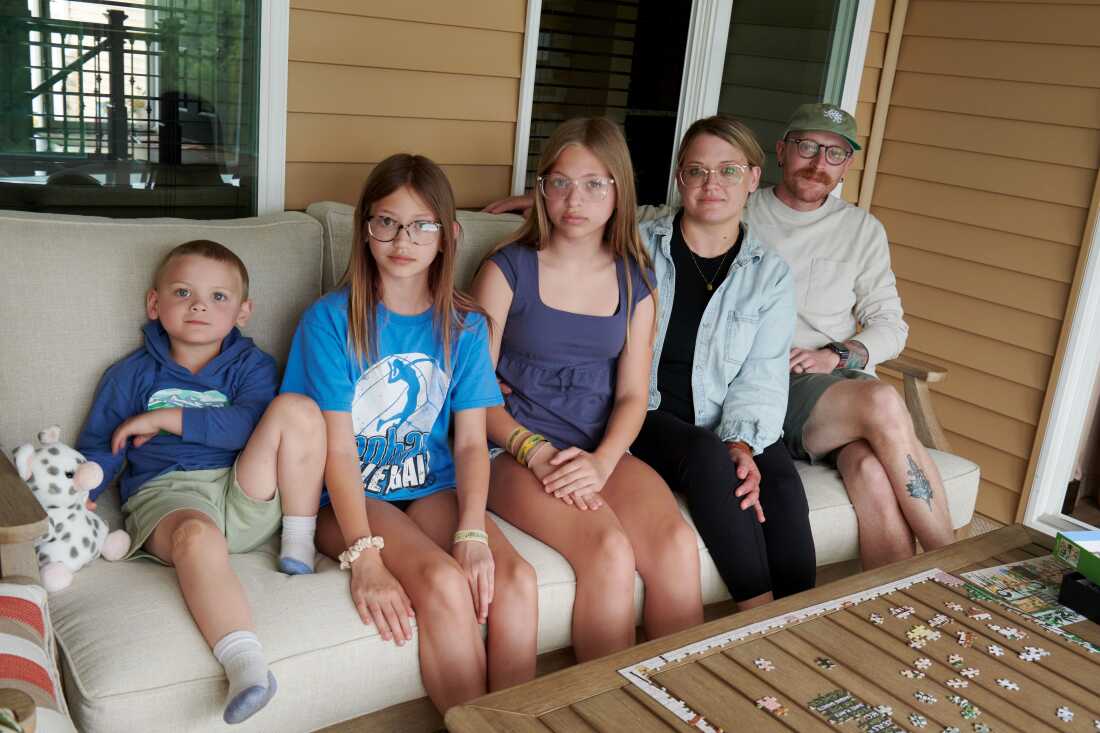 4 yaşındaki Jack Petersen, 11 yaşındaki Eden Svejda, 12 yaşındaki Piper Svejda, Amber Petersen ve Neil Petersen, 14 Haziran 2026 Pazar günü Iowa City, Iowa'da bir aile portresi için poz veriyor. Aile, Mason City, Iowa'da yaşıyor ve hafta sonu Amber'in ailesini ziyaret ediyordu. (NPR için Cliff Jette)
