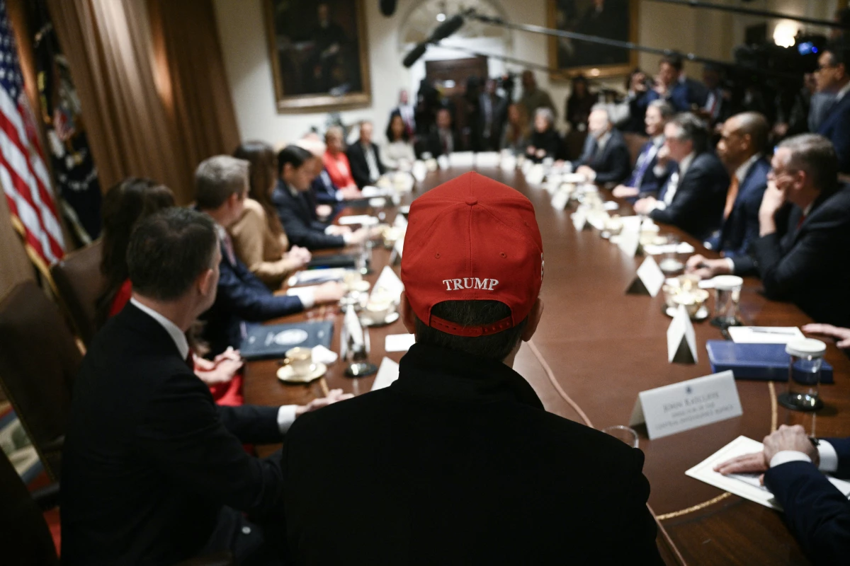 Elon Musk, wearing a red hat, looks on as President Donald Trump hosts a cabinet meeting at the White House on March 24.