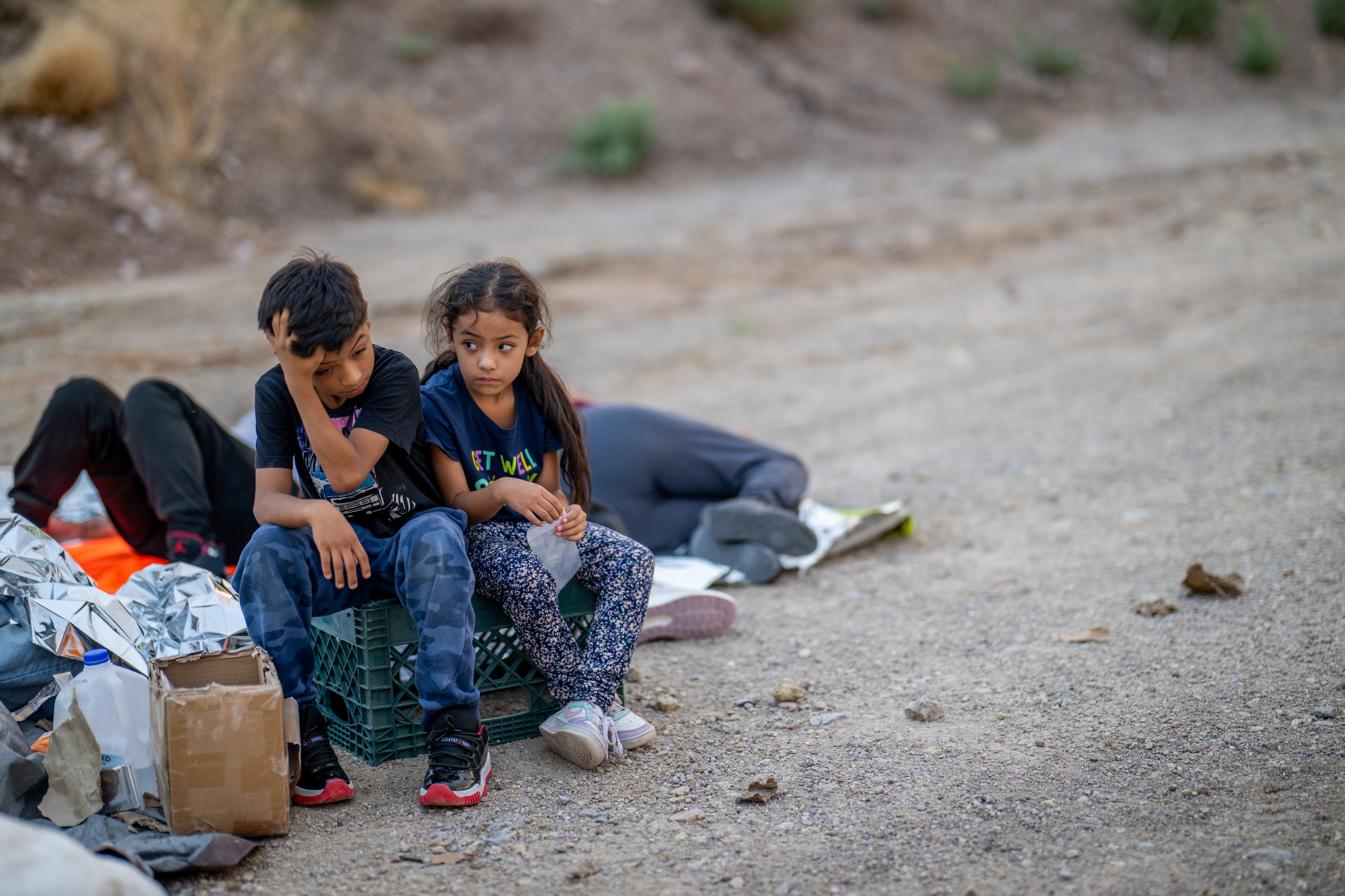 Children of the Rivera family look towards the sky while waiting to be apprehended by U.S. Customs and Border protection officers after crossing over into the U.S. in June 2024 in Ruby, Ariz.