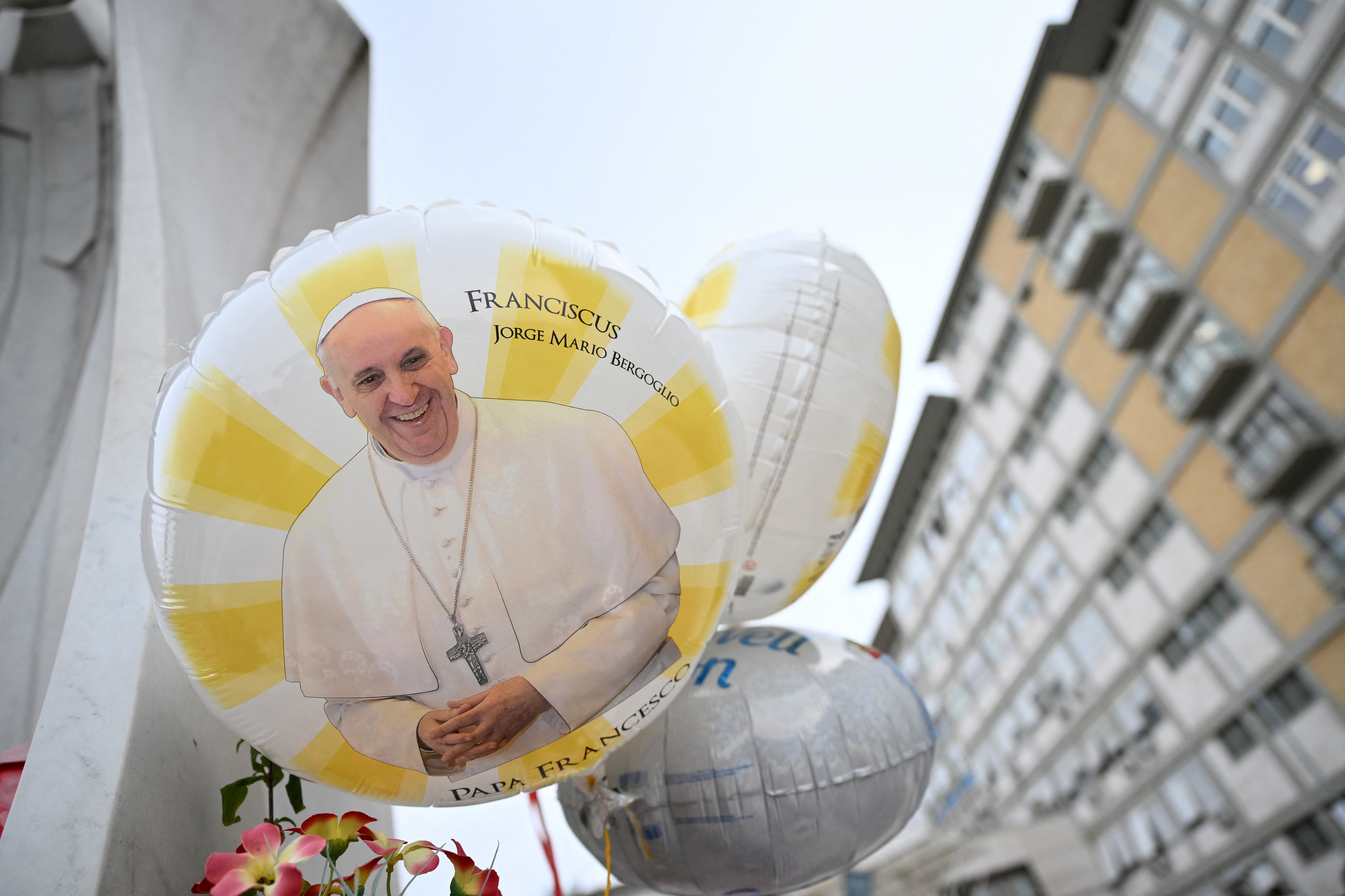 Balloons depicting Pope Francis are laid at the statue of John Paul II outside the Gemelli hospital where Pope Francis is hospitalized, in Rome on Feb. 24, 2025. Pope Francis, in critical condition in hospital with pneumonia, had a good night and was resting, the Vatican said Monday.