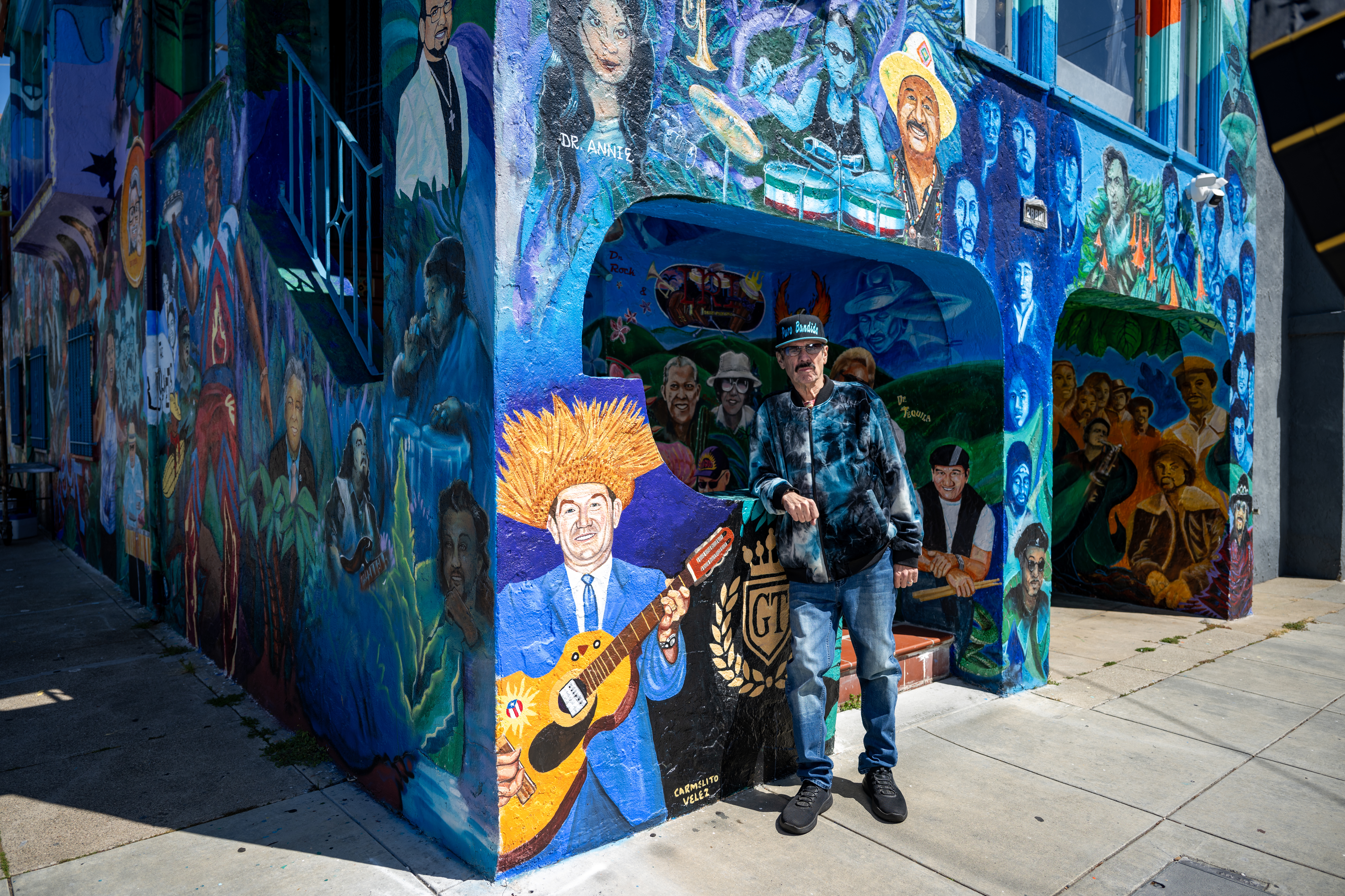 Richard Segovia stands in front of his house on 25th and York streets, known as the "Latin Rock House," in San Francisco in April. The home is covered in a large mural honoring dozens of musicians tied to the Mission District