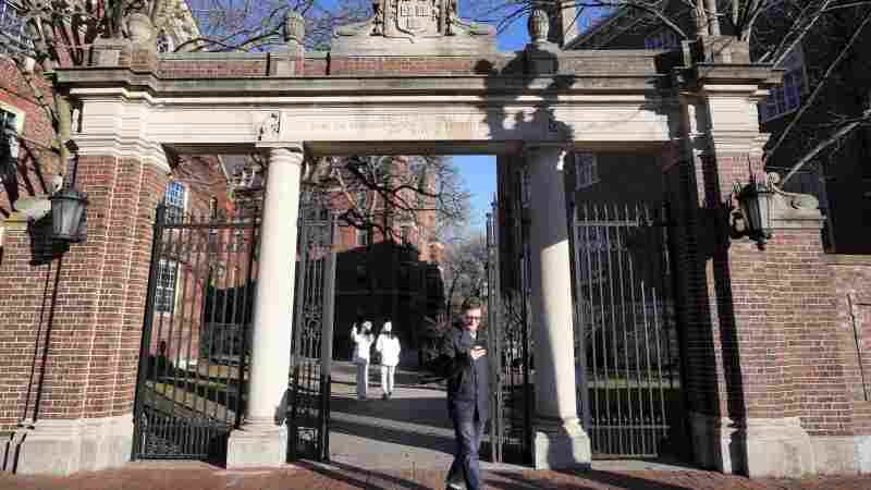 A passer-by walks through a gate to the Harvard University campus, Tuesday, Jan. 2, 2024, in Cambridge, Mass.