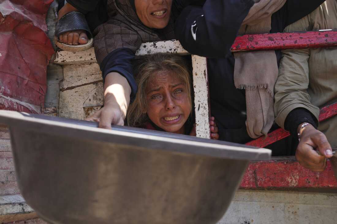 Palestinians struggle to get donated food at a community kitchen, in Gaza City, northern Gaza Strip, Saturday, July 26, 2025.