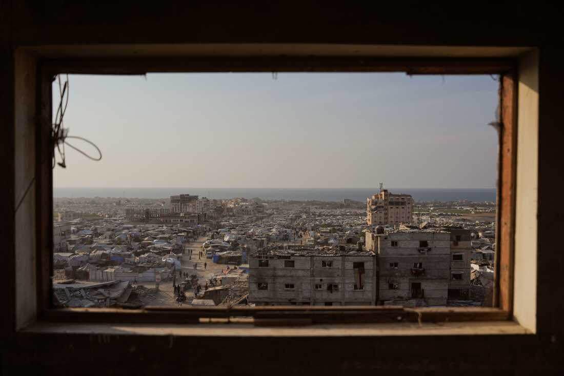 Displaced Palestinians walk through a makeshift tent camp in the Muwasi area of Khan Younis, in the Gaza Strip, Saturday, Nov. 8,2025. 