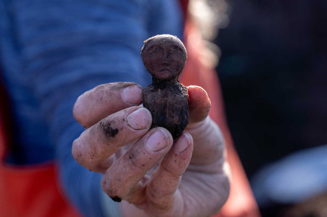 Charlotta Hillerdal holds up a wooden doll found in the soil at Nunalleq.