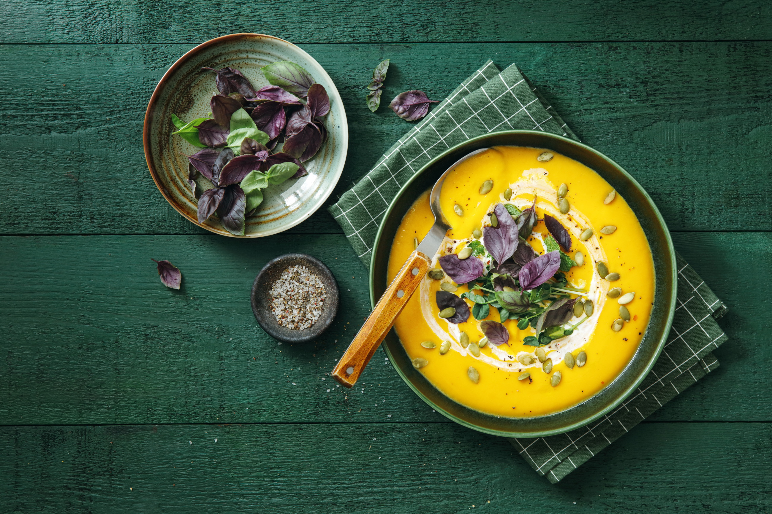 Top view of creamy orange soup on a dark green background.