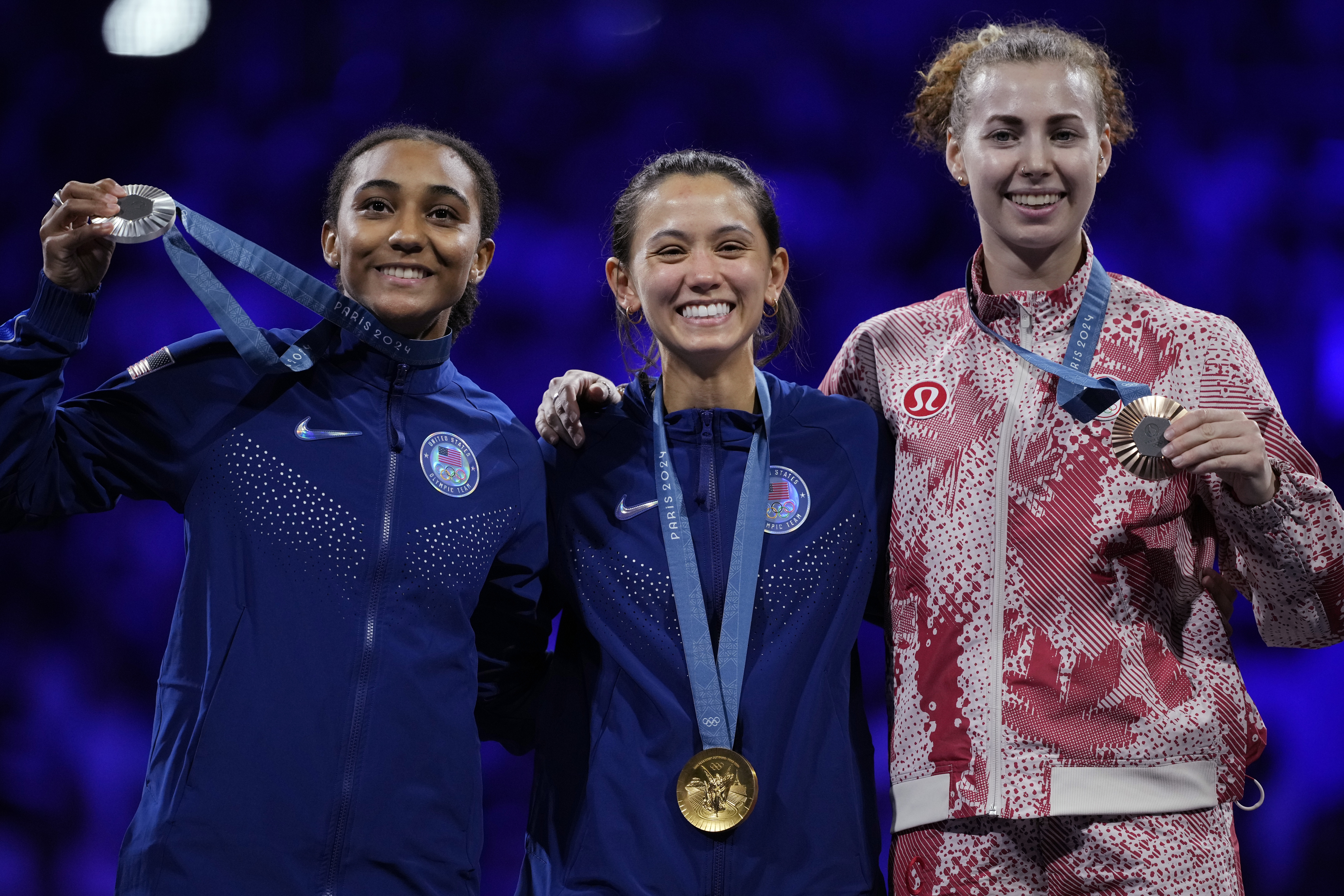 United States' Lee Kiefer, center, winner of the gold medal of the women's individual Foil competition, celebrates on the podium with silver medal winner United States' Lauren Scruggs, left, and bronze medal winner Canada's Eleanor Harvey during the Paris Olympics on Sunday. (AP)